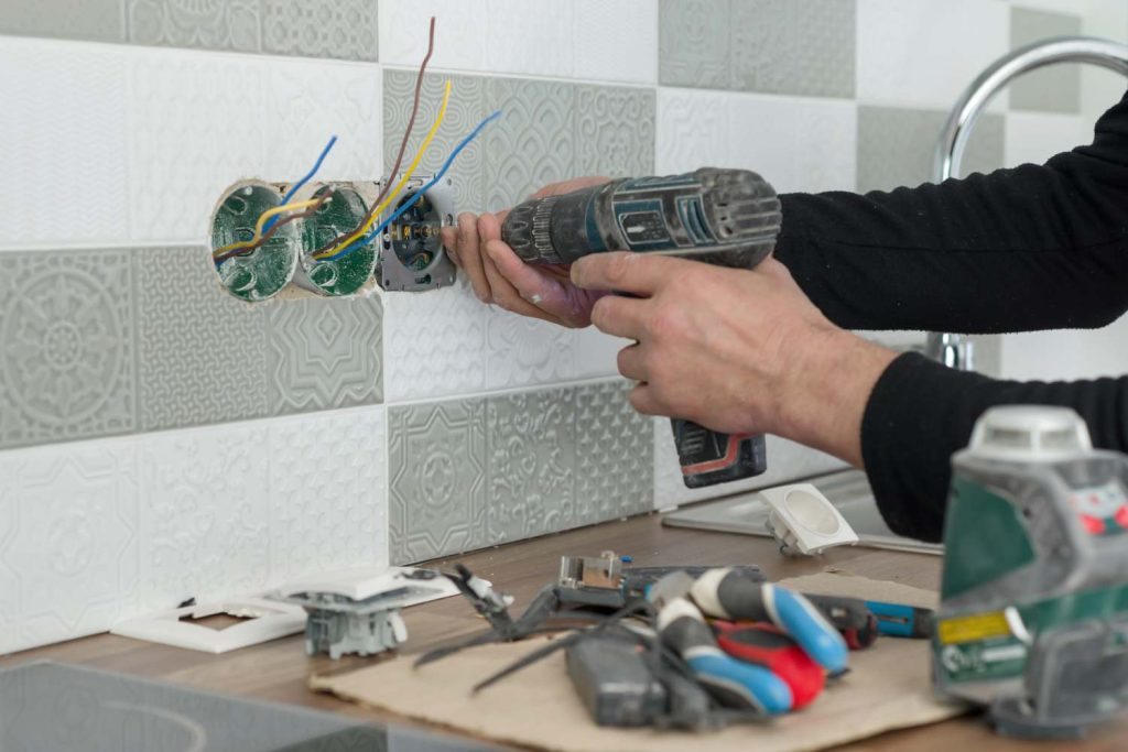 artisan électricien effectuant une rénovation électrique a Grenoble sur une prise